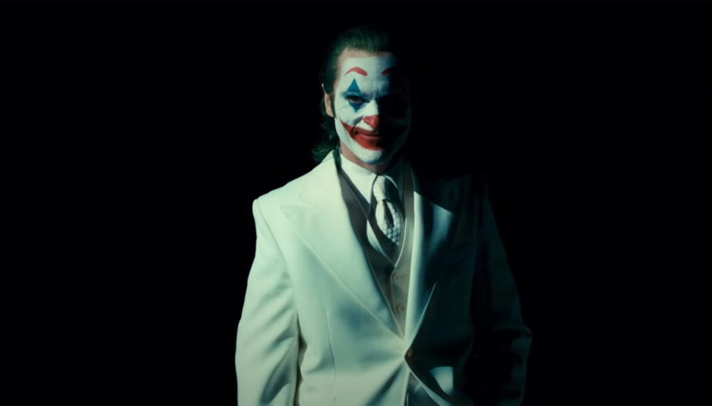 Joaquin Phoenix vestito di bianco in una scena di Arkham in Joker: Folie à Deux (2024) di Todd Phillips 